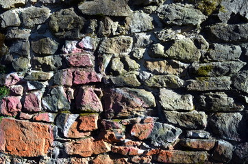 Dunkle Natursteinmauer mit Farbresten