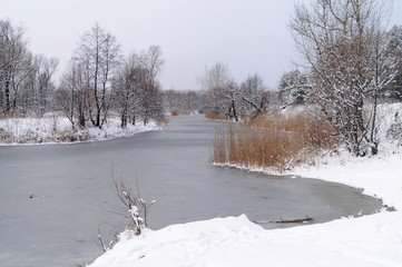 Winter landscape with frozen river and forest in the frost