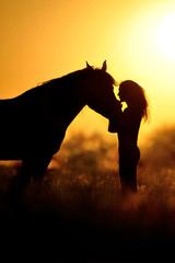 Obraz premium Girl and horse silhouette at sunset