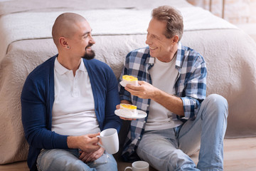 Gay couple eating cupcakes at home
