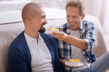 Delighted homosexual couple eating cupcakes together