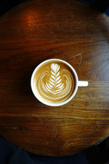 cup of latte art coffee on wooden background