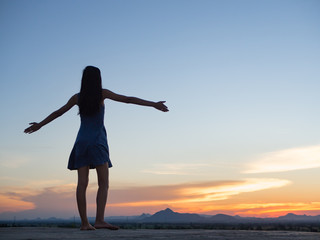 Silhouette of free woman enjoying freedom feeling happy at sunset. relaxing woman in pure happiness