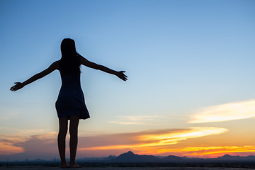 Fototapeta premium Silhouette of free woman enjoying freedom feeling happy at sunset. relaxing woman in pure happiness