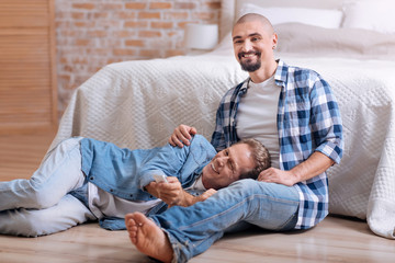 Delighted gay couple watching television together at home