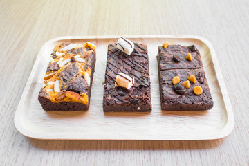 Dark chocolate brownies on wooden background.	