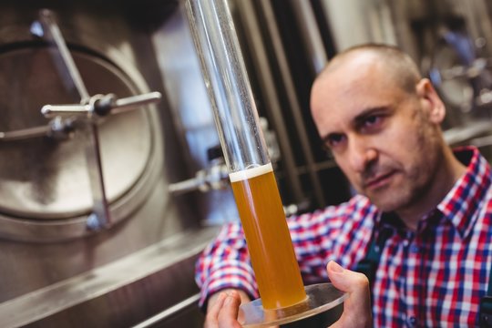 Owner inspecting beer in glass tube