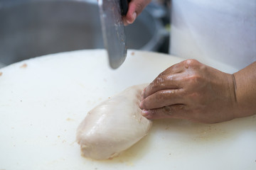 Fototapeta premium Food preparation. Man's hands cutting chicken 