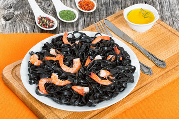 black noodles with king prawns on white dish