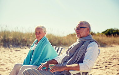happy senior couple in chairs on summer beach