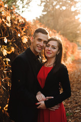 Young couple of pretty girl and man walk outdoors in park on aut