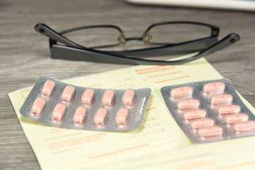 Ein Krankenschein, Tabletten und eine Brille