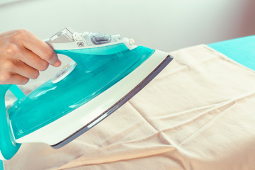 Closeup of woman ironing clothes on ironing board