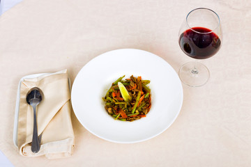 Meat dish with vegetables in a plate and a glass of red wine