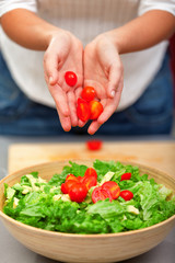 Woman making salad with cherry tomatoes in the kitchen