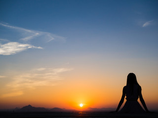 Fototapeta premium Silhouette of free woman enjoying freedom feeling happy at sunset. Serene relaxing woman in pure happiness