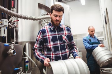 Manufacturer and worker lifting kegs