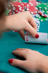 Young woman holding pocket aces poker cards in front of gambling