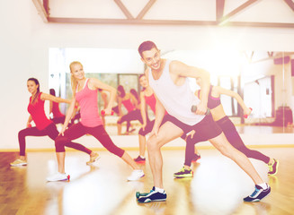 Obraz premium group of smiling people working out with dumbbells