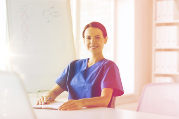 happy female doctor or nurse writing to clipboard