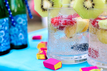 Champagne with fruit in a beautiful glass. Colorful Cakes on the occasion. Picnic table.
