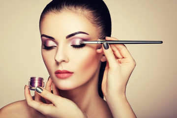 Makeup artist applies eye shadow. Beautiful woman face. Perfect makeup. Makeup detail. Beauty girl...