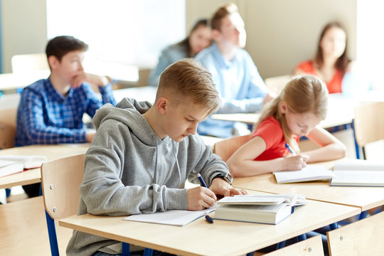 group of students with books writing school test