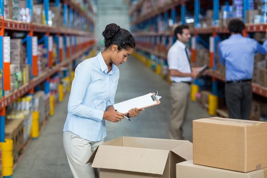 Female warehouse worker with a clipboard checking the boxes 