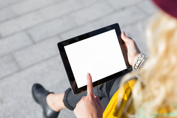 Person sitting outside and using blank screen tablet