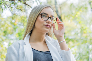 a young woman doctor, blonde in glasses in park outdoors