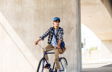 young hipster man with bag riding fixed gear bike