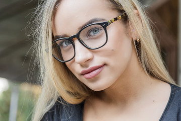 portrait of a young woman, blonde, glasses, outdoors in the park