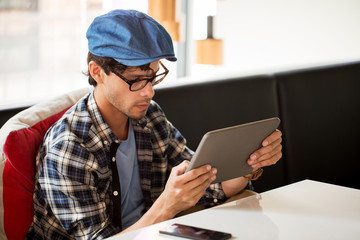 man with tablet pc sitting at cafe table