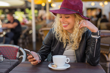 Woman sitting at cafe and using smartphone