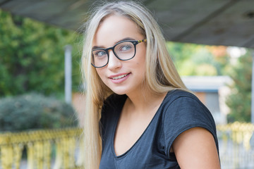 portrait of a young woman, blonde, glasses, outdoors in the park