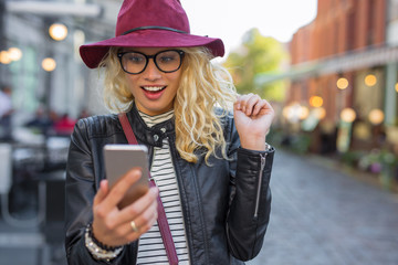 Woman looking at her smartphone in pleasant surprise