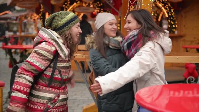 Happy Meeting of Three Friends Hugging in the Cristmas Market, Laughing Girlfriends Having Fun in the Xmas Market . Merry Christmas and Happy New Year