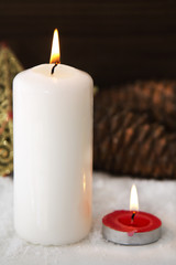 Christmas card with candles and pine cones on snow
