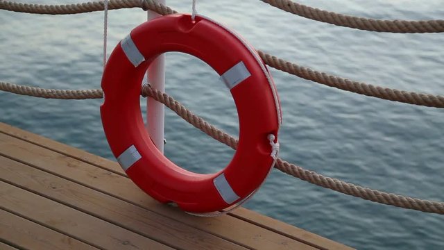 Close up of red life buoy over blue calm sea water background. Real time full hd video footage.