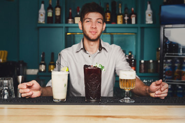 Young Barman offers cocktails in night club bar