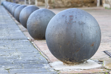 Round bollards in perspective separating sidewalk from road.