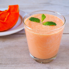 Close up of a glass of papaya smoothies on a wooden table.