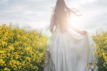 Bride running on chamomile field