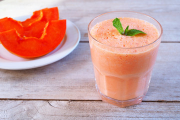Close up of a glass of healthy papaya smoothies on a wooden table.