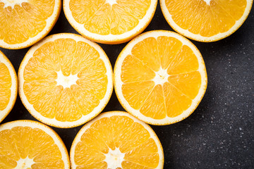Fresh and juicy half cut oranges on dark stone table