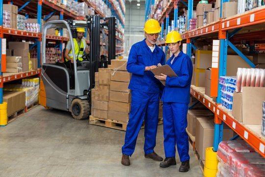 Warehouse workers discussing with clipboard