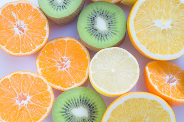 Sliced juicy citrus fruits. Citrus fruit background with sliced oranges, lemons, kiwi and tangerines. Healthy eating, natural vitamins.