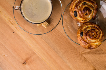 Coffee cup with cinnabons on wooden background.