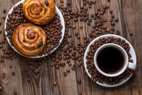Coffee cup with coffee bean and cinnabons on wooden background.