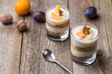 Fresh homemade dessert with biscuits, yogurt, tangerines and walnuts, served in a glass